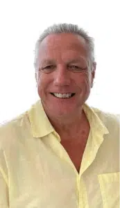 A man with white hair and a yellow shirt.